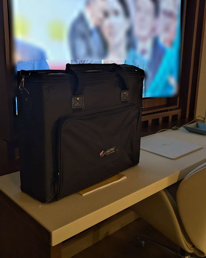 Il kit LinkoNet in camera d'albergo la sera prima delle riprese, televisore sfocato sullo sfondo
