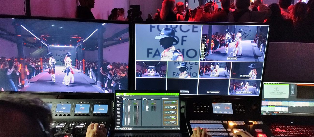 Postazione di regia video con mixer e monitor multiview durante un evento di moda